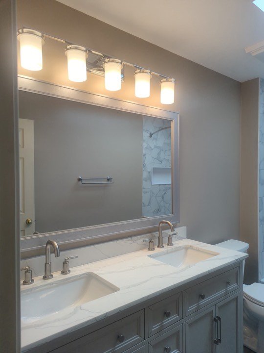 Double bathroom vanity with stone top and wall sconces.