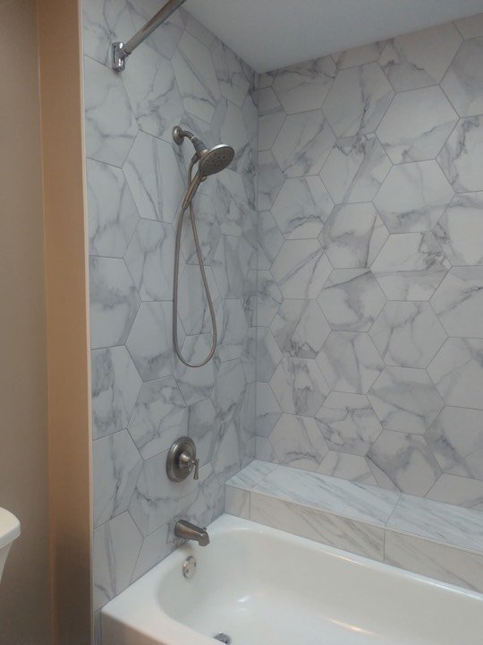 Marble tiled tub and shower surround with a chrome fixture.