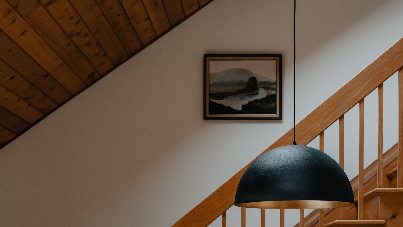 A wooden staircase with a timber ceiling and pendant light.