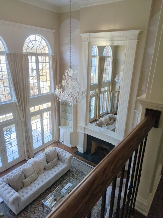 Staircase with railing overlooking a two-storey living room.